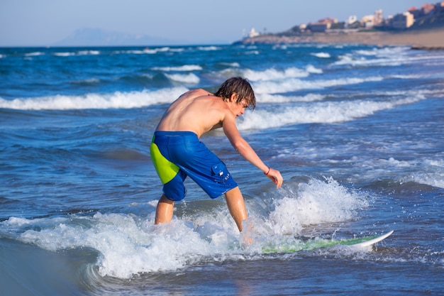 Chico surfista surfeando olas en la playa