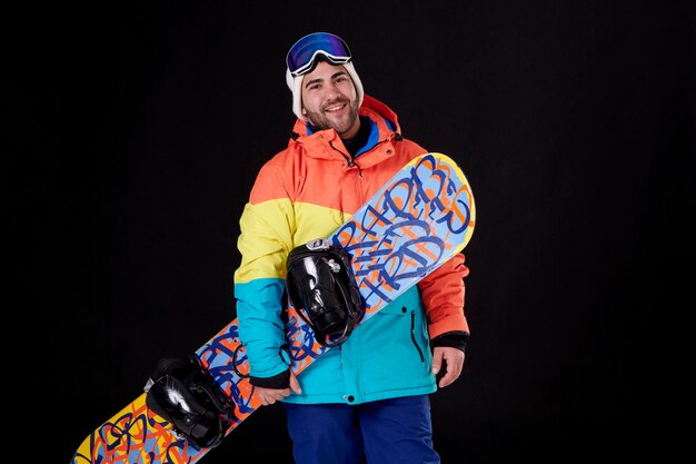 Foto chico con una tabla de snowboard sonriendo y mirando a la cámara.