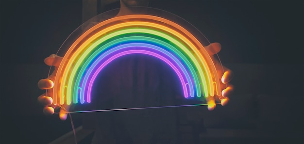 Chico tiene arco iris de neón led en las manos en la noche