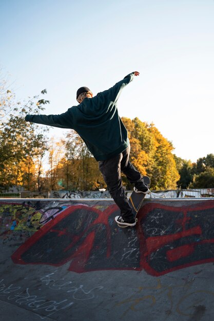 Foto chico de tiro completo haciendo trucos en patineta afuera