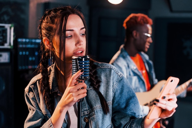 Chico toca guitarra chica canta hombre afroamericano con chica blanca ensayando juntos en el estudio