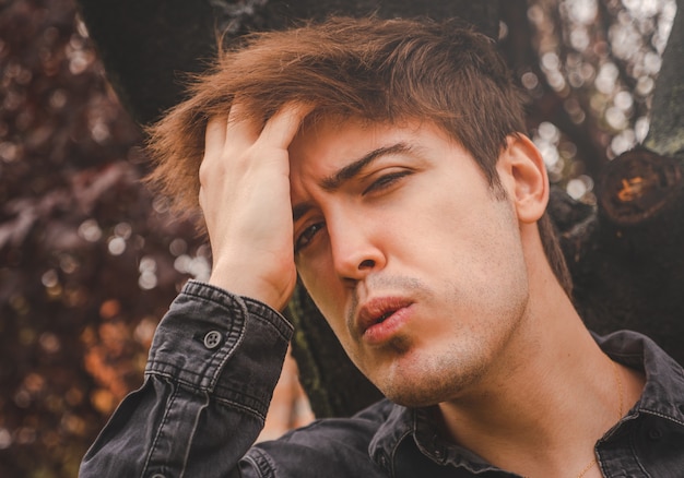 Chico tocando su cabello mirando a la cámara en un parque