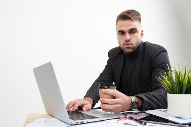 El chico tomando café en el lugar de trabajo.