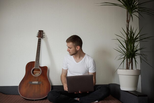 El chico trabaja en casa en su computadora portátil.