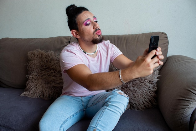 Chico transexual tomando una selfie o una videollamada con su móvil en casa