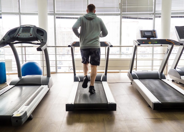 Chico trotando en una cinta de correr en el gimnasio Ejercicio físico y estilo de vida saludable