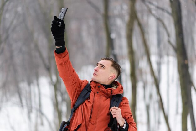 Chico turista está tratando de atrapar una red móvil en el bosque frío de invierno