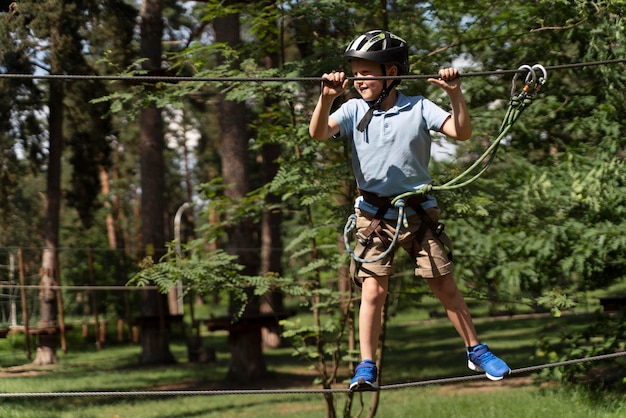 Foto chico valiente divirtiéndose en un parque de aventuras