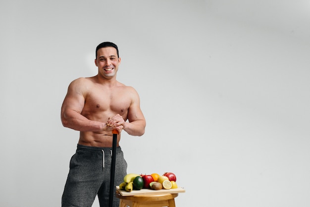 Chico vegano sexy con un torso desnudo posando en el estudio junto a la fruta. Dieta. Dieta saludable