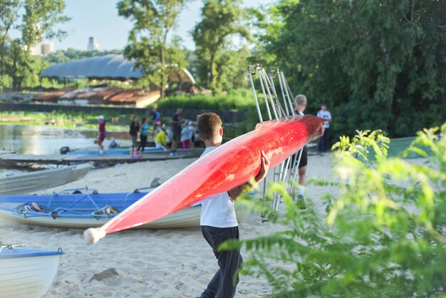 Chicos adolescentes caminando con bote deportivo en kayak al río