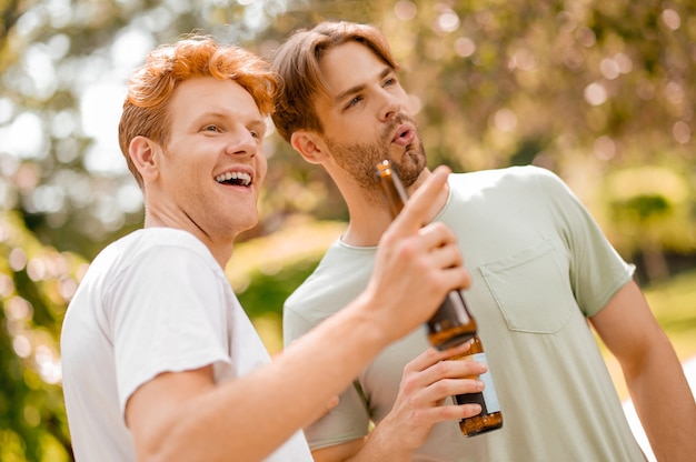 Chicos con botellas mirando con interés en el parque.