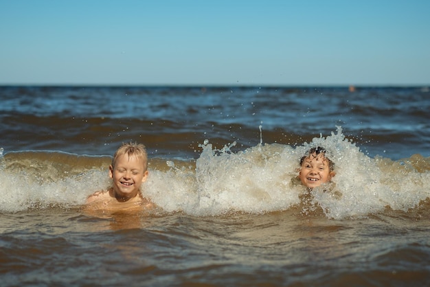 Chicos caucásicos lindos de 78 años nadan en el mar con grandes salpicaduras Los niños disfrutan nadando en el océano Vacaciones vacaciones con niños