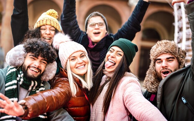 Chicos y chicas multiculturales tomándose selfies con ropa de abrigo