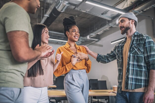 Foto chicos y chicas sonrientes que se comunican felizmente en la oficina