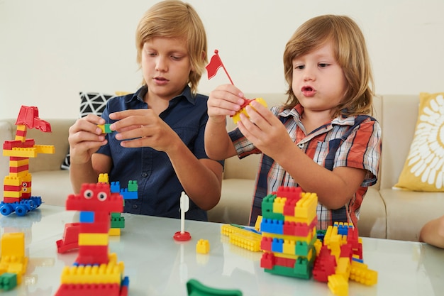 Foto chicos creativos jugando con ladrillos de plástico.