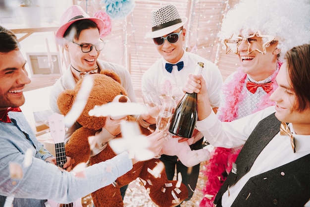 Chicos gay abriendo y bebiendo champagne en la fiesta.