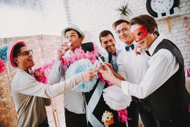 Chicos gay tintinean copas de champán en la fiesta.