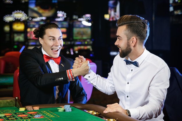 Chicos guapos jugando a la ruleta en el casino