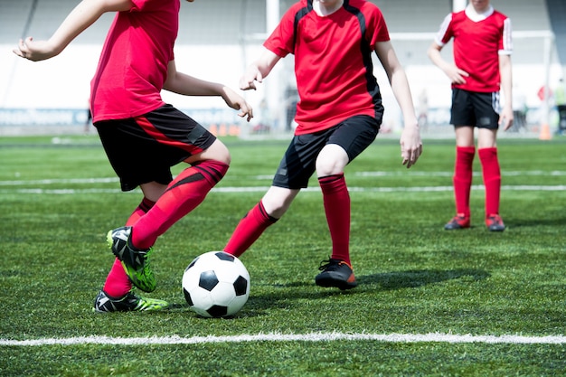 Chicos irreconocibles jugando al fútbol en el campo