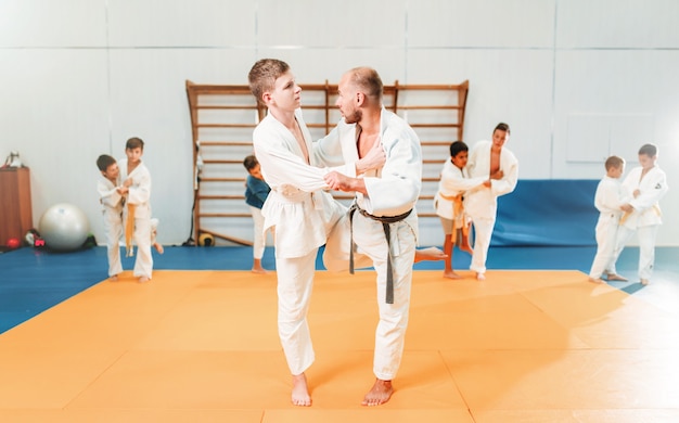 Chicos en kimono practican artes marciales en el gimnasio deportivo