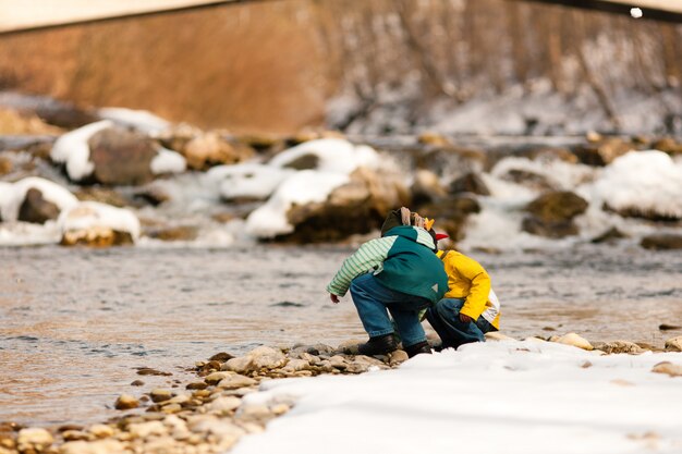 Chicos con nieve en el río en invierno