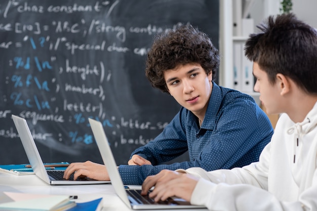 Uno de los chicos que mira a su compañero de clase durante el trabajo individual mientras ayuda a su amigo o consulta sobre una pregunta difícil en la lección.