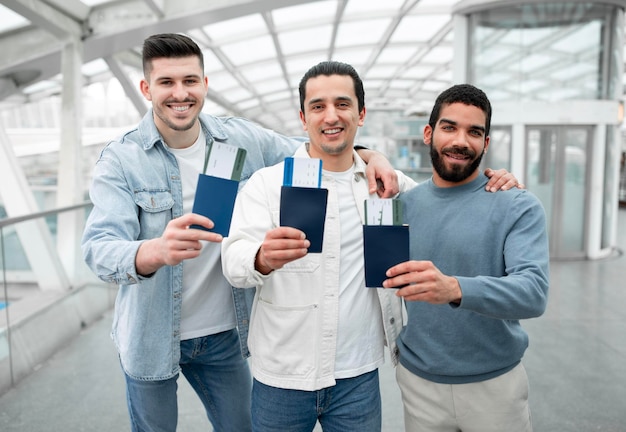 Chicos viajeros abrazándose mostrando tarjetas de embarque en el aeropuerto moderno