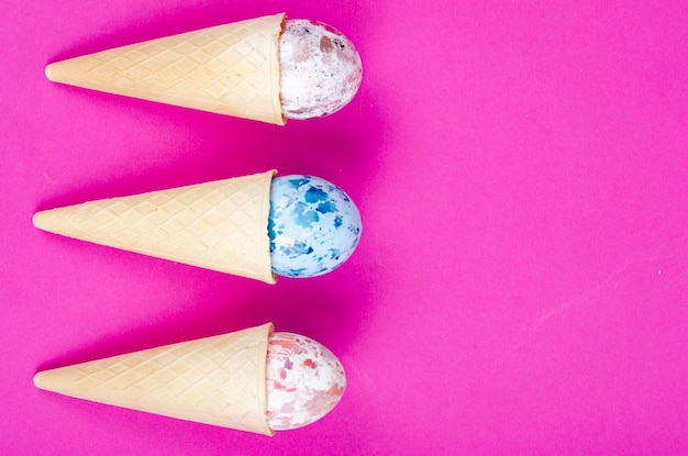 Chifres de waffle de sorvete de baunilha com ovos de decoração em fundo rosa. Minimalismo. Conceito criativo de Páscoa. Foto de estúdio.