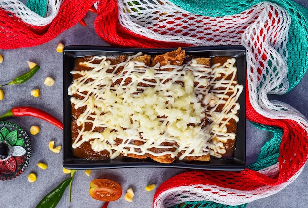 Chilaquiles con pollo y crema agria y salsa con bandera mexicana en un fondo gris