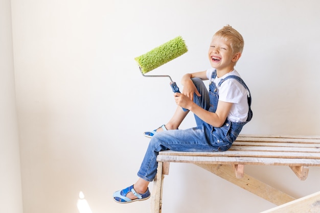 Child Boy Builder hält Bauwerkzeuge in einer Wohnung mit weißen Wänden