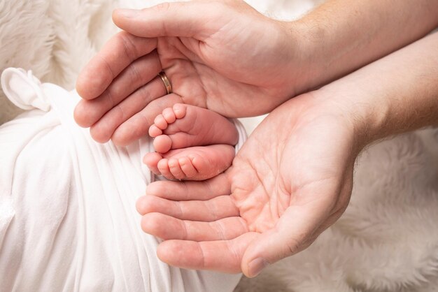 Children39s Fuß in den Händen von Mutter, Vater, Eltern, Füße eines winzigen Neugeborenen, Nahaufnahme, kleine Babybeine, Mutter und ihr Kind, glückliches Familienkonzept, schönes Konzeptbild der Mutterschaft, stockfoto