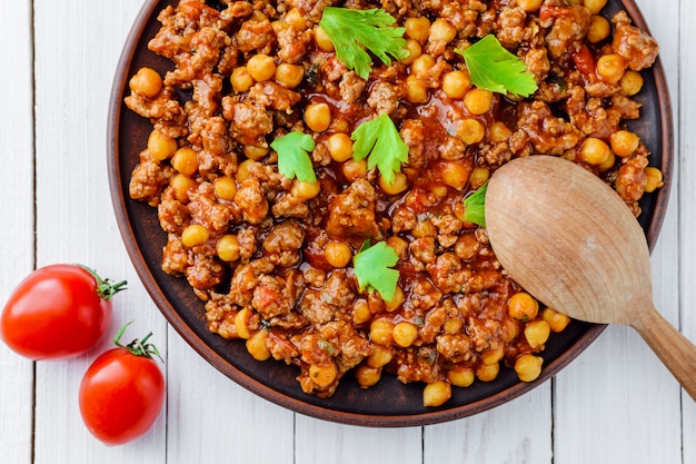 Chile com carne de porco e grão de bico em uma placa sobre uma mesa de madeira branca