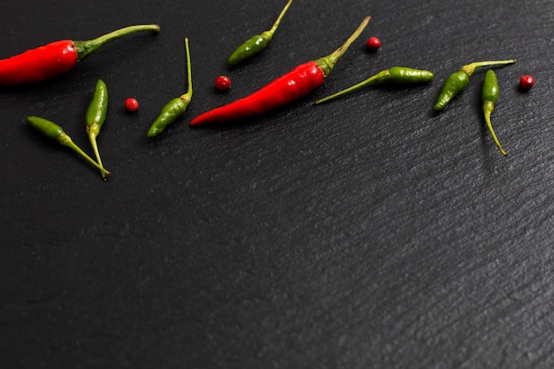 Chile picante del fondo rojo de la presentación de la comida y chile verde en tablero negro de la pizarra