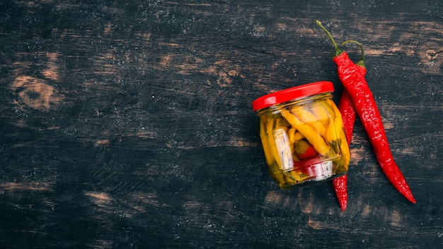 Chile de pimientos picantes en escabeche Sobre un fondo de madera negra Vista superior Copiar espacio para el texto