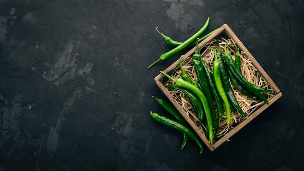 Chile verde fresco en una caja de madera Sobre la mesa negra Vista superior Espacio libre para texto