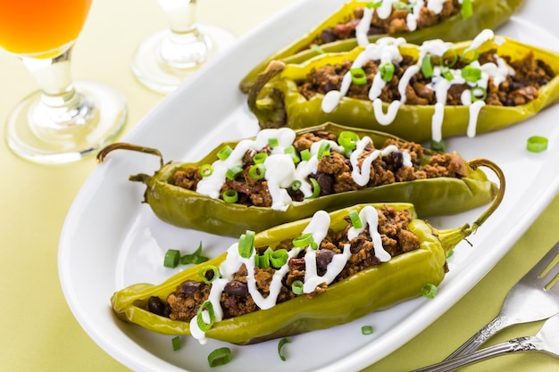 Chiles rellenos de ternera con chipotle y frijoles aderezados con crema agria y cebolletas.