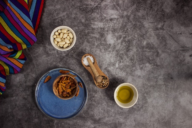 Chiles rojos de árbol, cacahuetes, sal, pimienta y aceite de oliva para preparar una comida mexicana sobre una pizarra dispuesta en el medio