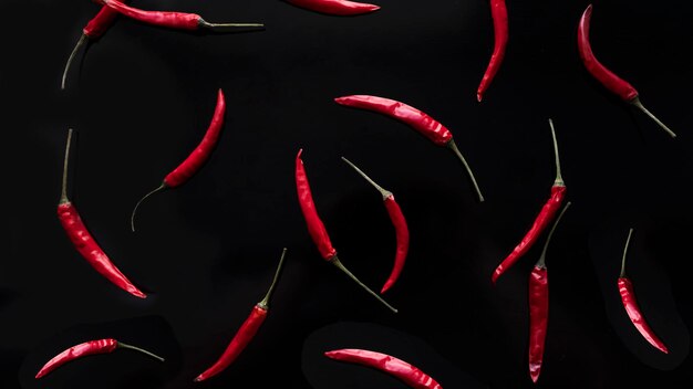 Foto chiles rojos flotando en el aire sobre un fondo negro