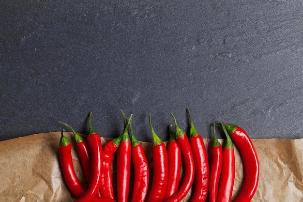 Chiles rojos frescos sobre pergamino y fondo de pizarra