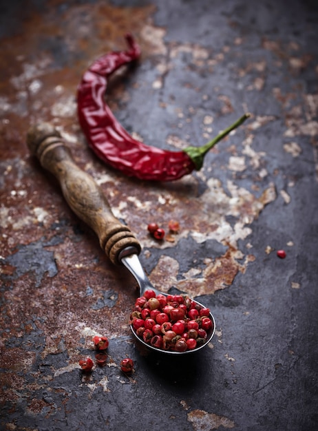 Foto chiles rojos y pimienta rosa sobre fondo de pizarra