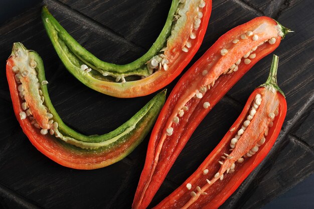 Chiles rojos y verdes cortados por la mitad en una tabla de madera