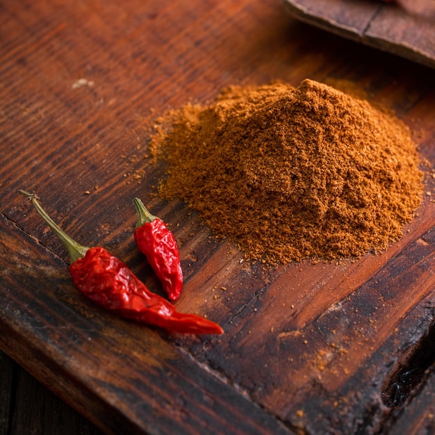 Chiles secos rojos picantes con condimento molido sobre una mesa de madera texutra