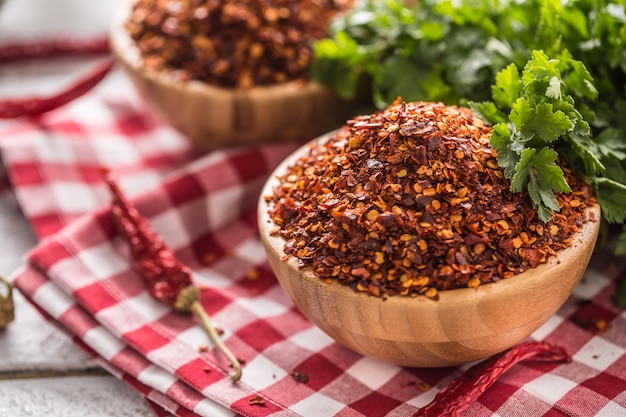 Chiles secos y triturados en cuencos de madera con hierbas de perejil.