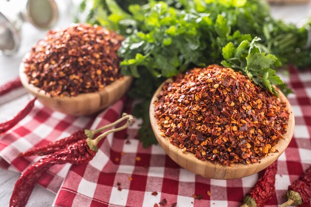 Chiles secos y triturados en cuencos de madera con hierbas de perejil.