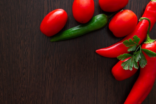 Chiles y tomates sobre un fondo oscuro de la madera