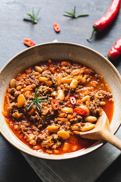 Chili Con Carne em tigela sobre fundo escuro Cozinha mexicana chili com carne ensopado de carne e legumes em molho de tomate Vista superior