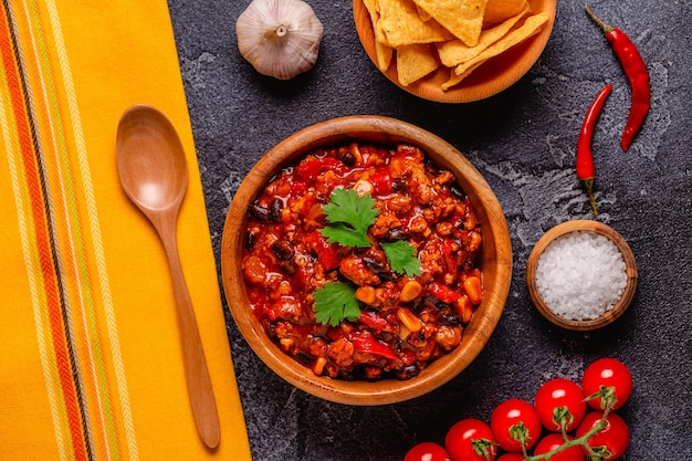 Chili con Carne in einer Schüssel auf dunklem Hintergrund, mexikanische Küche, Draufsicht