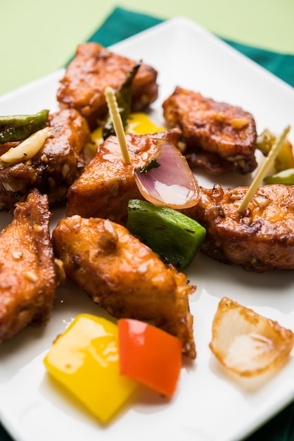 Chili Paneer oder würziger Hüttenkäse, serviert in weißem Teller mit Paprika und Zwiebeln, beliebtes indisches Vorspeisemenü, selektiver Fokus