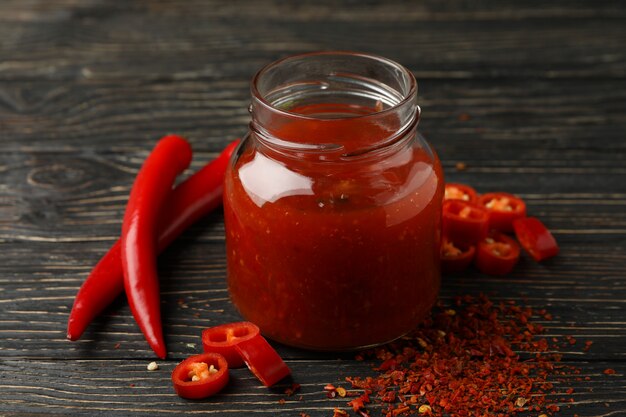 Chili-Pfeffer und Glas Sauce auf Holz