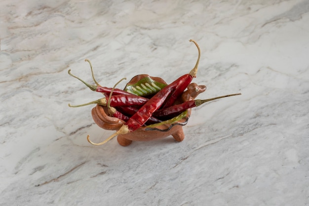 Chilis de Arbol oder getrocknete rote Chilischoten in einem Tontopf auf einer grauen Marmorbar